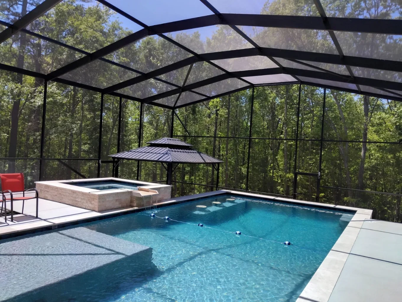 Professional installation crew assembling aluminum screen enclosure on residential patio with tools and materials staged nearby.