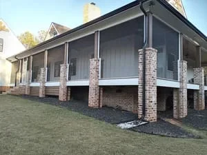 Elevated screen room with brick columns and white trim framing on residential home