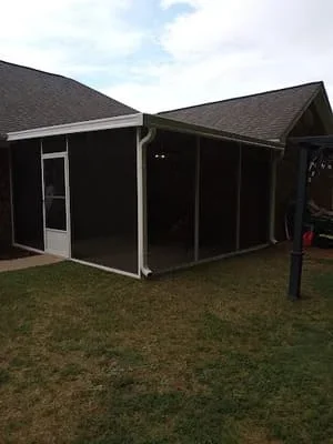 Black screen room with gabled roof and white entry door in residential backyard