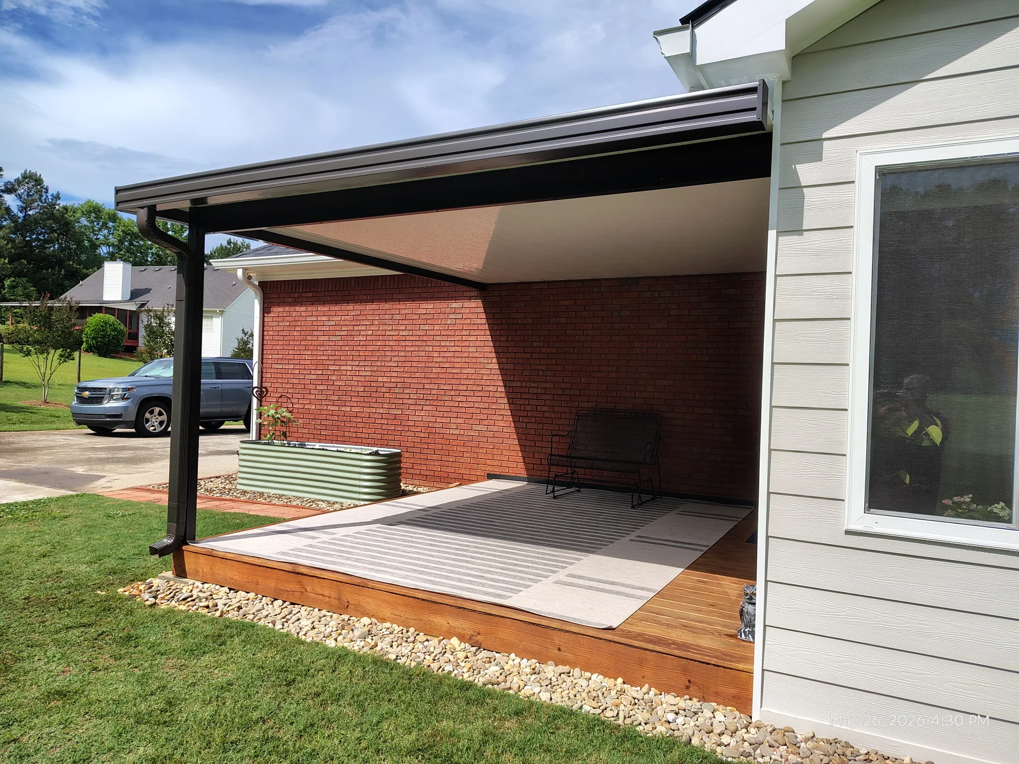 Black aluminum pergola with retractable shade over composite deck and wooden platform