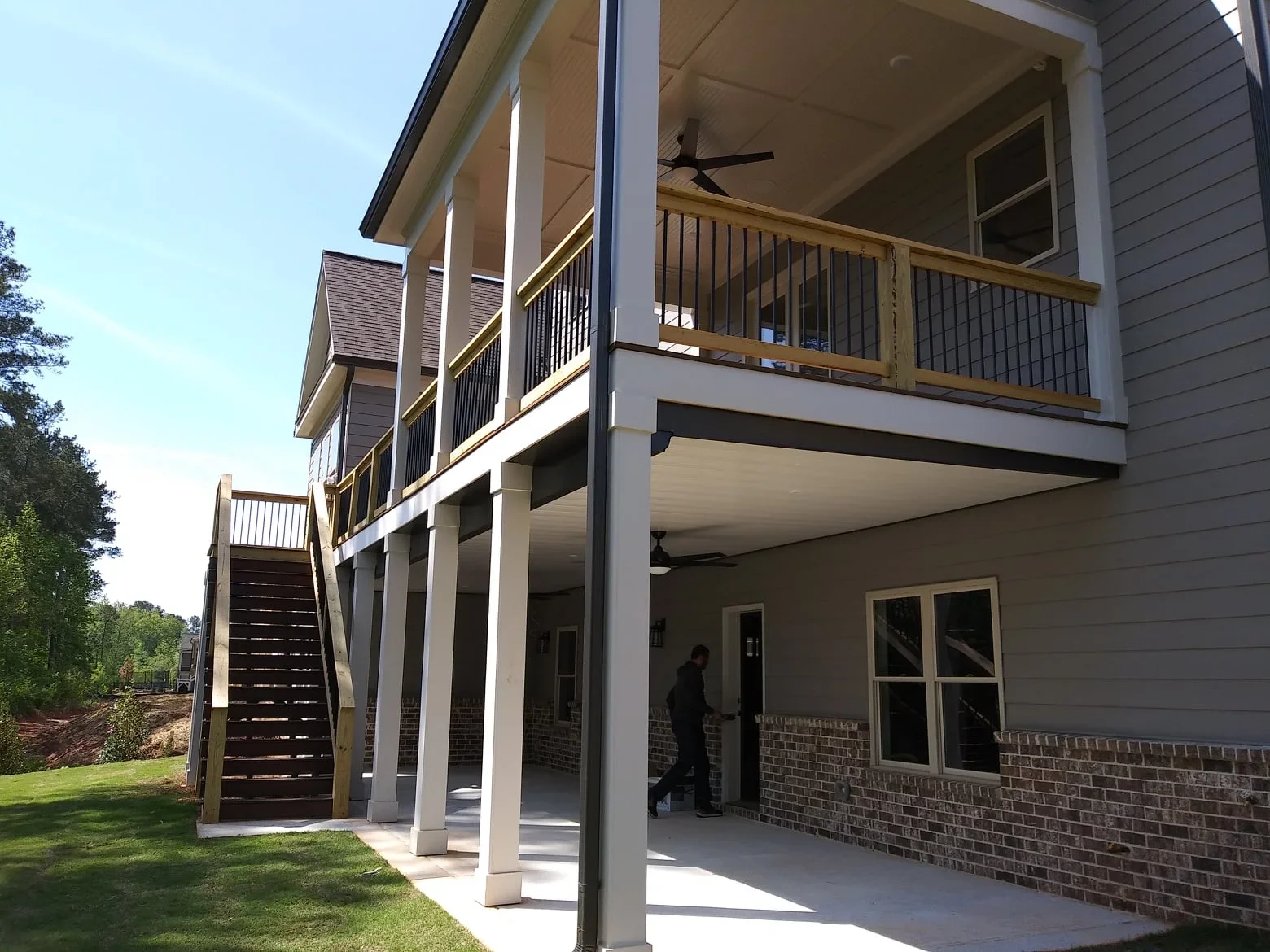 Two-story deck with under-deck system, white posts, metal railings, and covered lower patio area