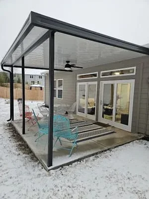 Black-framed screen room with patio cover attached to residential home in winter