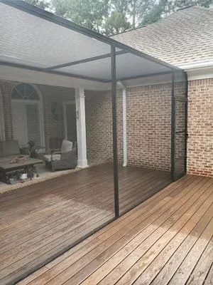 Black-framed screen room with composite decking attached to brick home