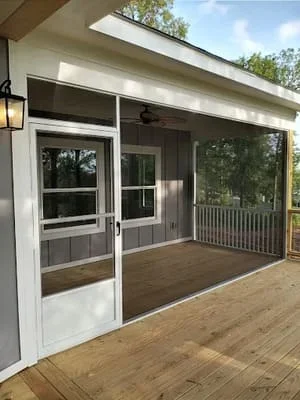 White aluminum screen room with dark mesh panels and glass door on composite deck