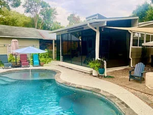 Black-framed screen room next to curved swimming pool with concrete patio