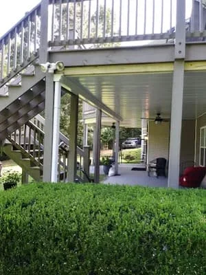 Elevated deck with attached screen room enclosure and manicured hedge landscaping