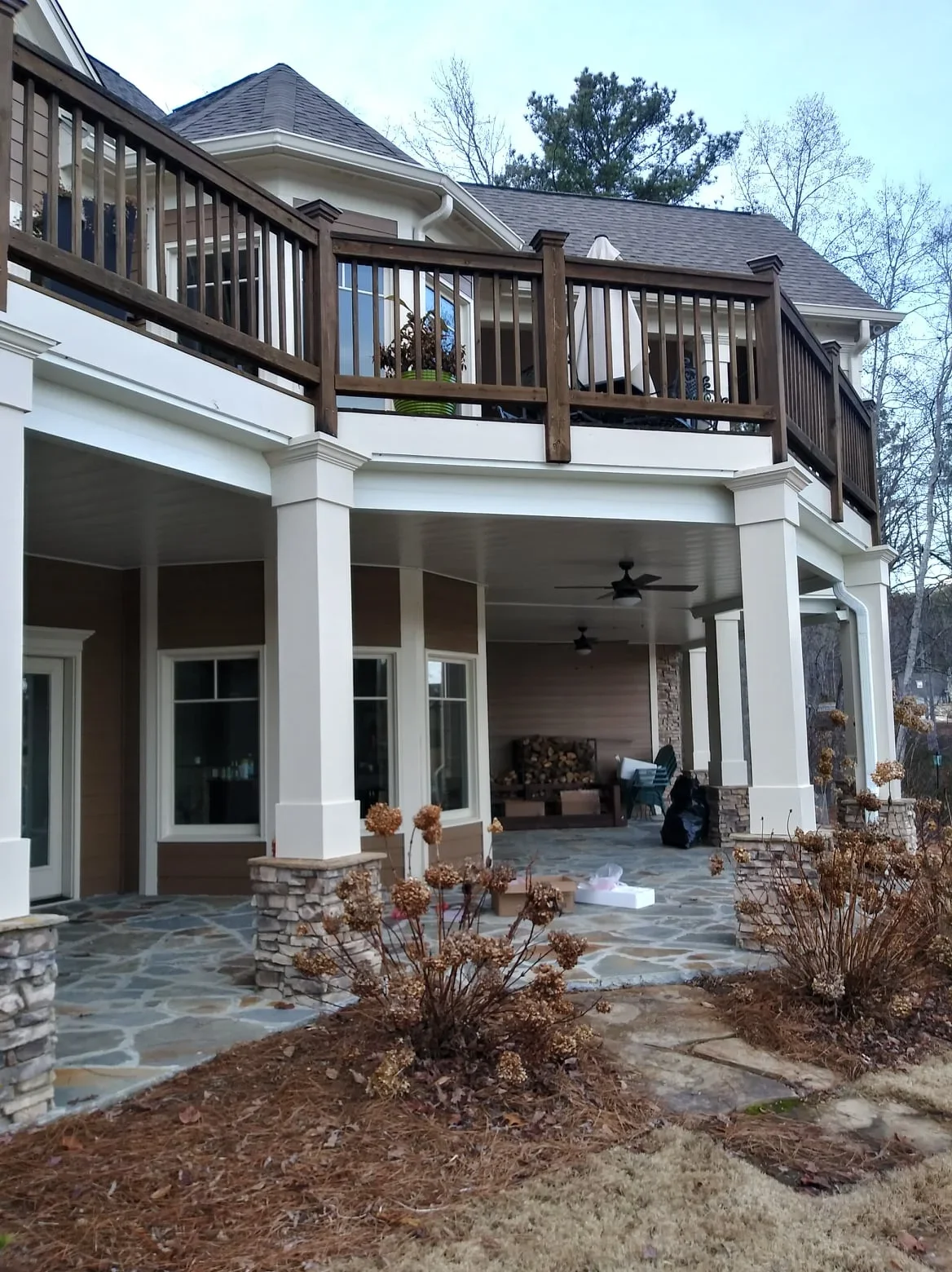 White under-deck ceiling with black ceiling fans installed beneath elevated deck with dark wood railings