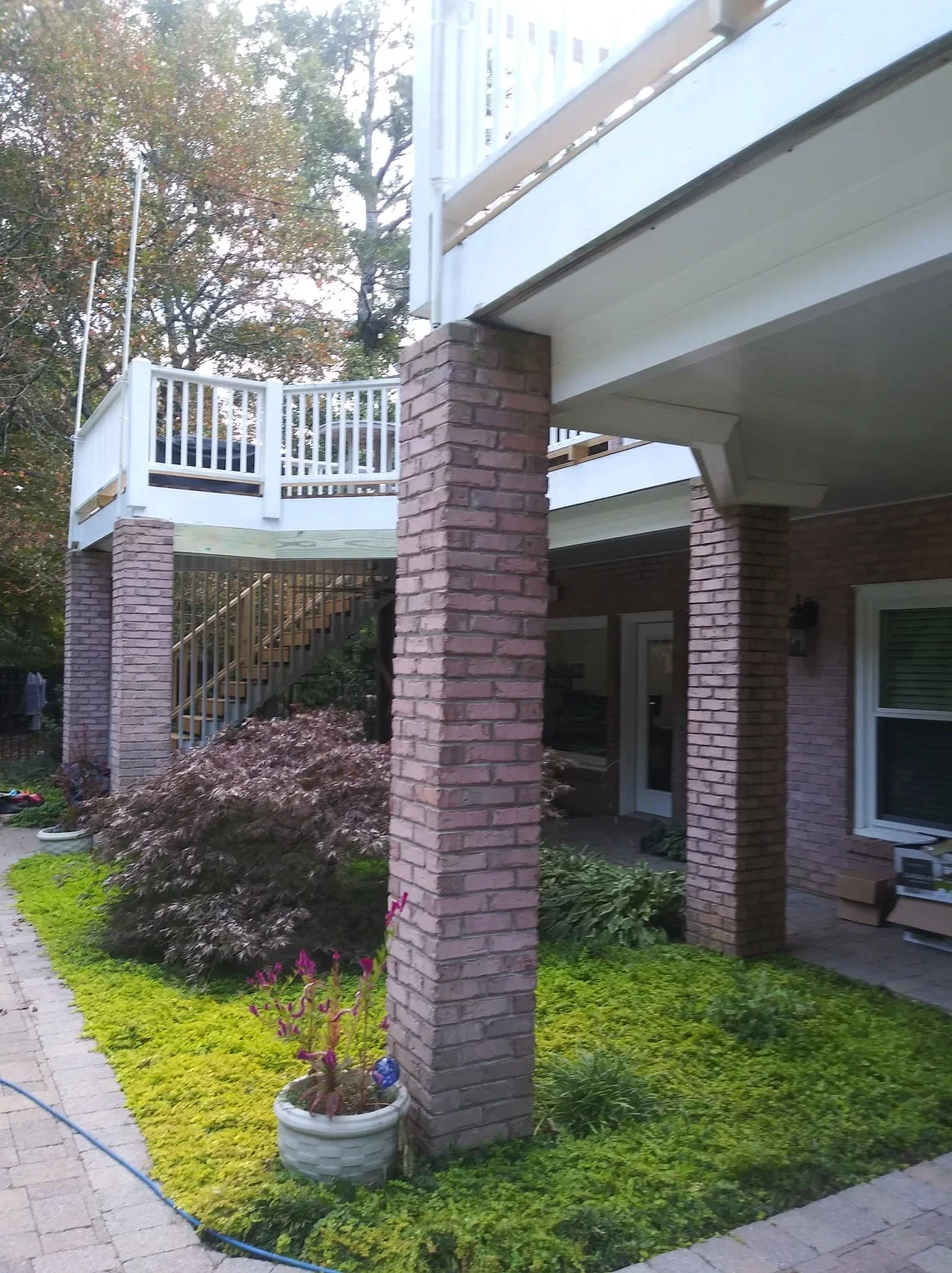 Under-deck drainage system with brick columns, metal railings, and covered patio space