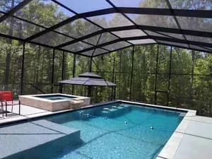 Screened pool enclosure with aluminum frame and clear views of wooded surroundings