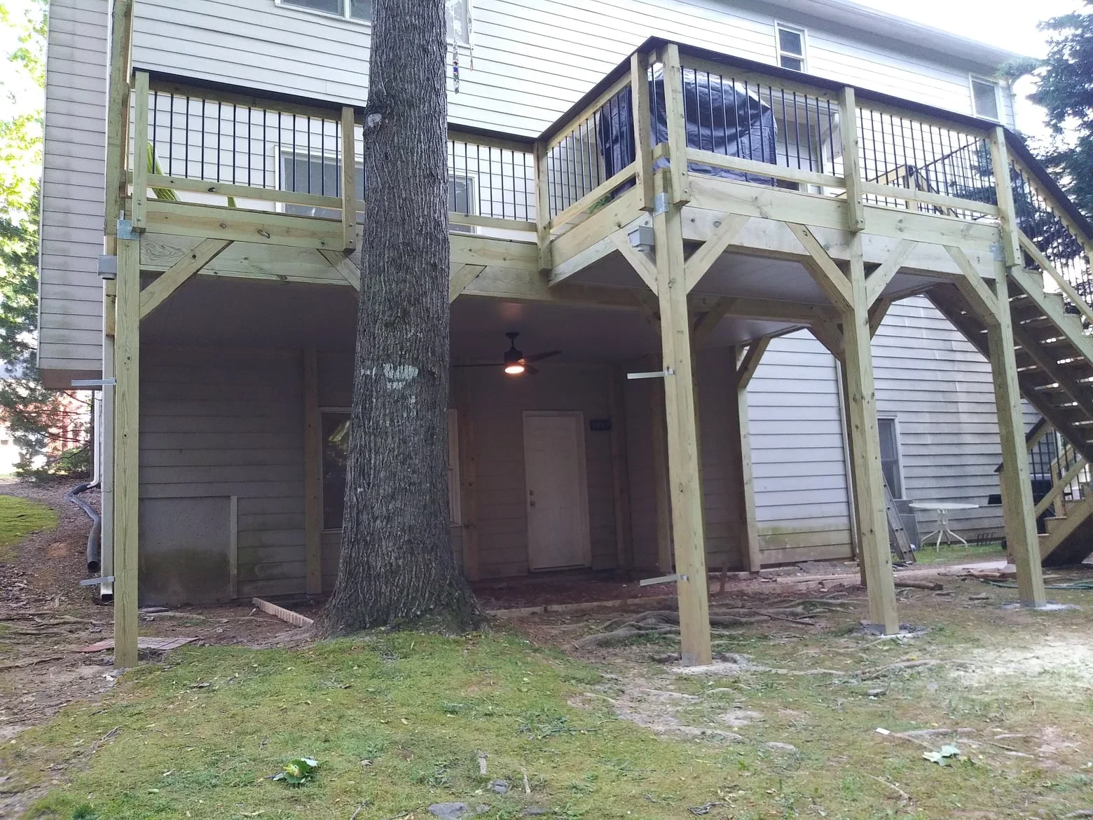 Aluminum under-deck drainage system with metal mesh screening, timber posts, and integrated ceiling
