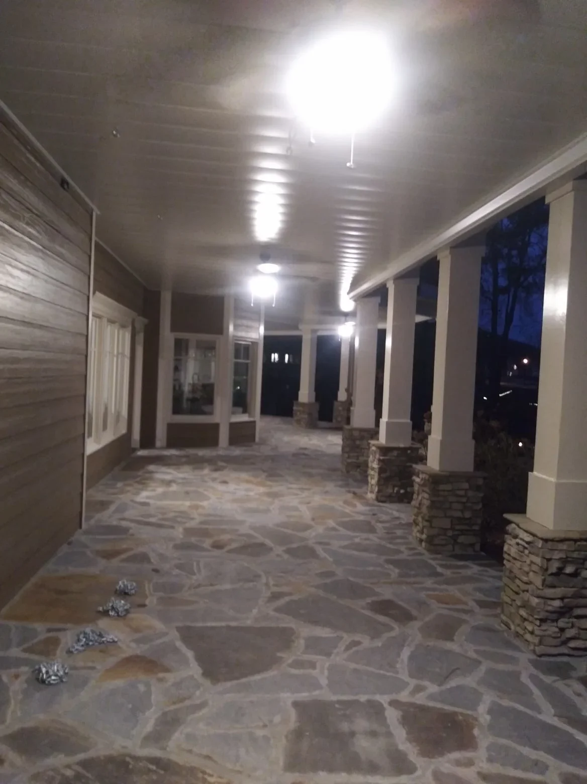 Aluminum under-deck ceiling with LED lighting, white columns, and stone veneer supports