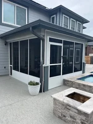 Black-framed screen room with sliding glass doors and white trim on concrete patio