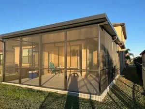 Modern aluminum screen room with full screening panels and roof overhang in residential backyard