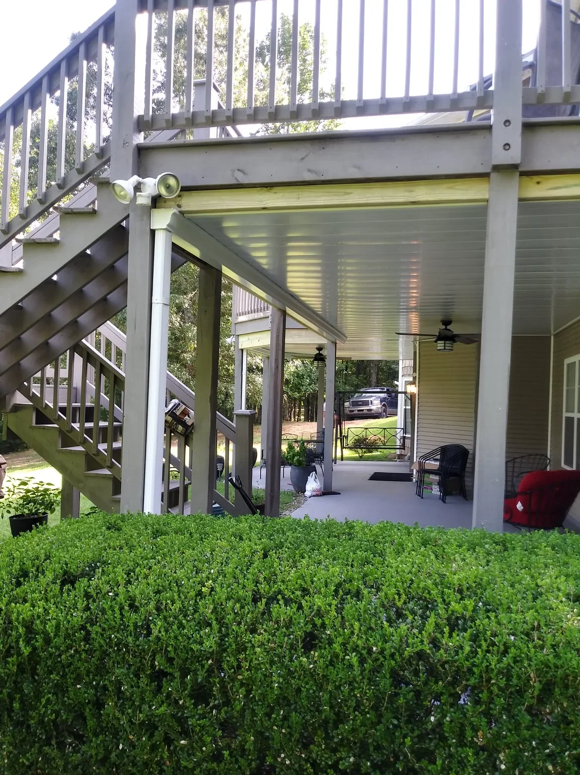 Aluminum louvered under-deck ceiling with metal posts and integrated lighting under elevated composite deck