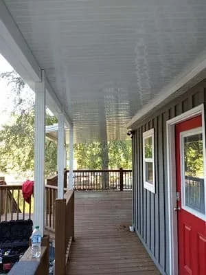 Covered screen room with composite deck, aluminum frame, and red entry door