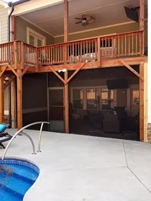 Two-story wooden deck with black mesh screen room enclosure and ceiling fan