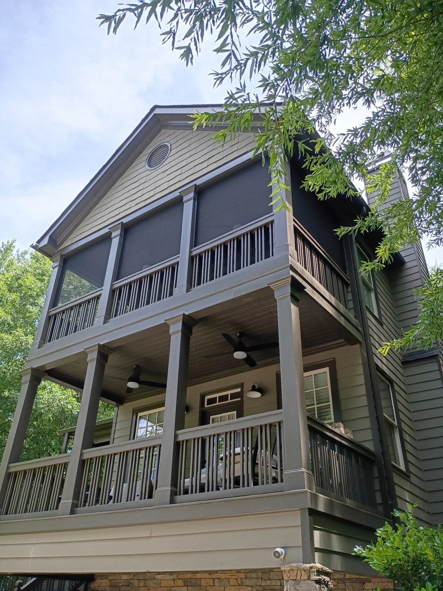 Two-story screen room with metal balusters, ceiling fans, and dark screening on upper and lower decks
