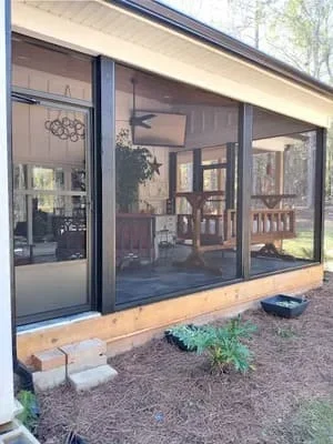 Black-framed screen room with glass panels and wood base trim on residential patio