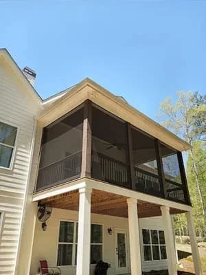 Two-story wooden screen room with upper and lower decks attached to residential home