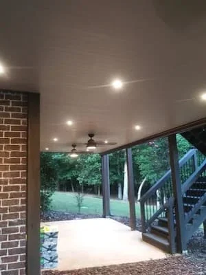 Covered screen room with recessed lighting and black aluminum frame overlooking backyard