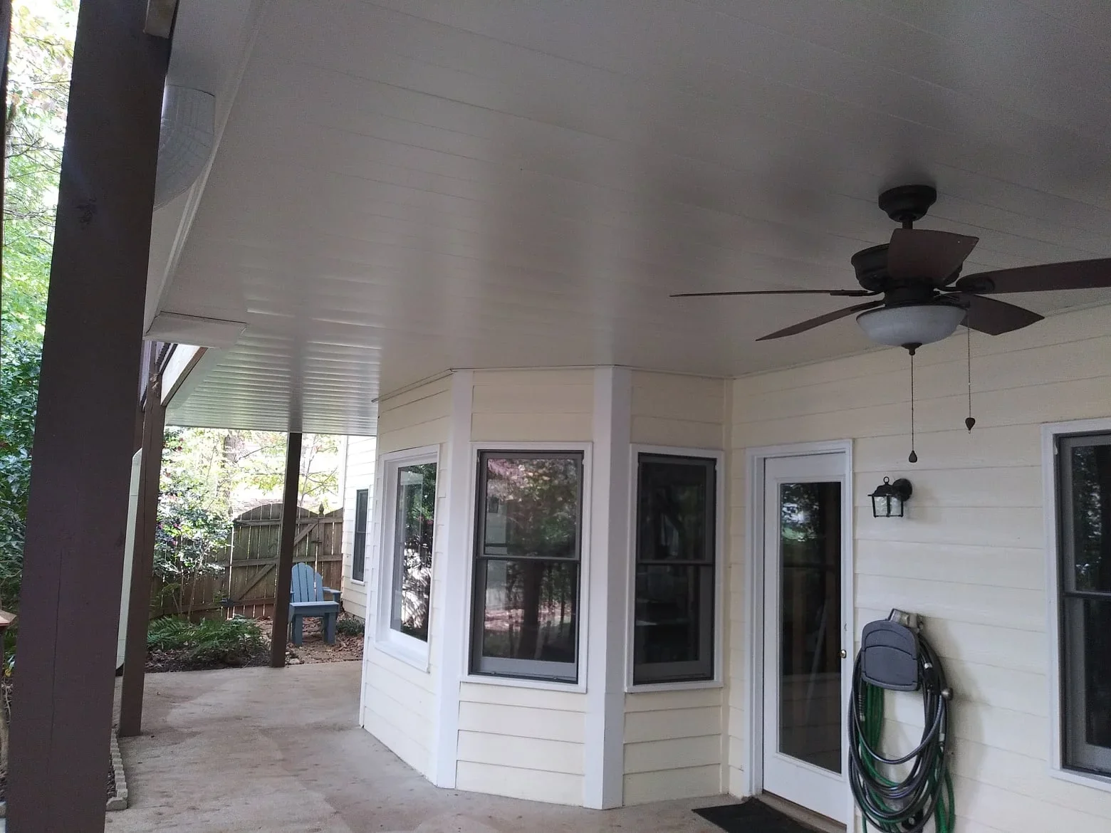 Aluminum soffit patio cover with ceiling fan, French doors, and concrete pad