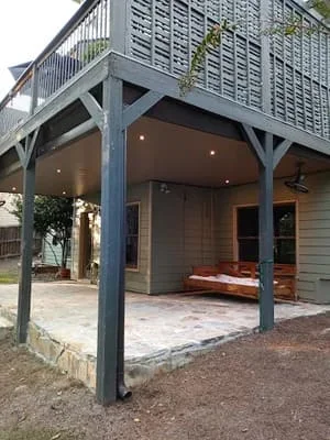 Modern screen room with blue posts, recessed lighting, and motorized shade system attached to residential home