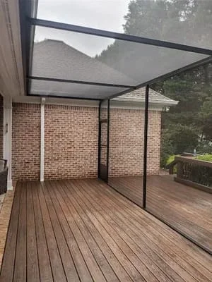 Black-framed screen room with composite deck attached to brick home