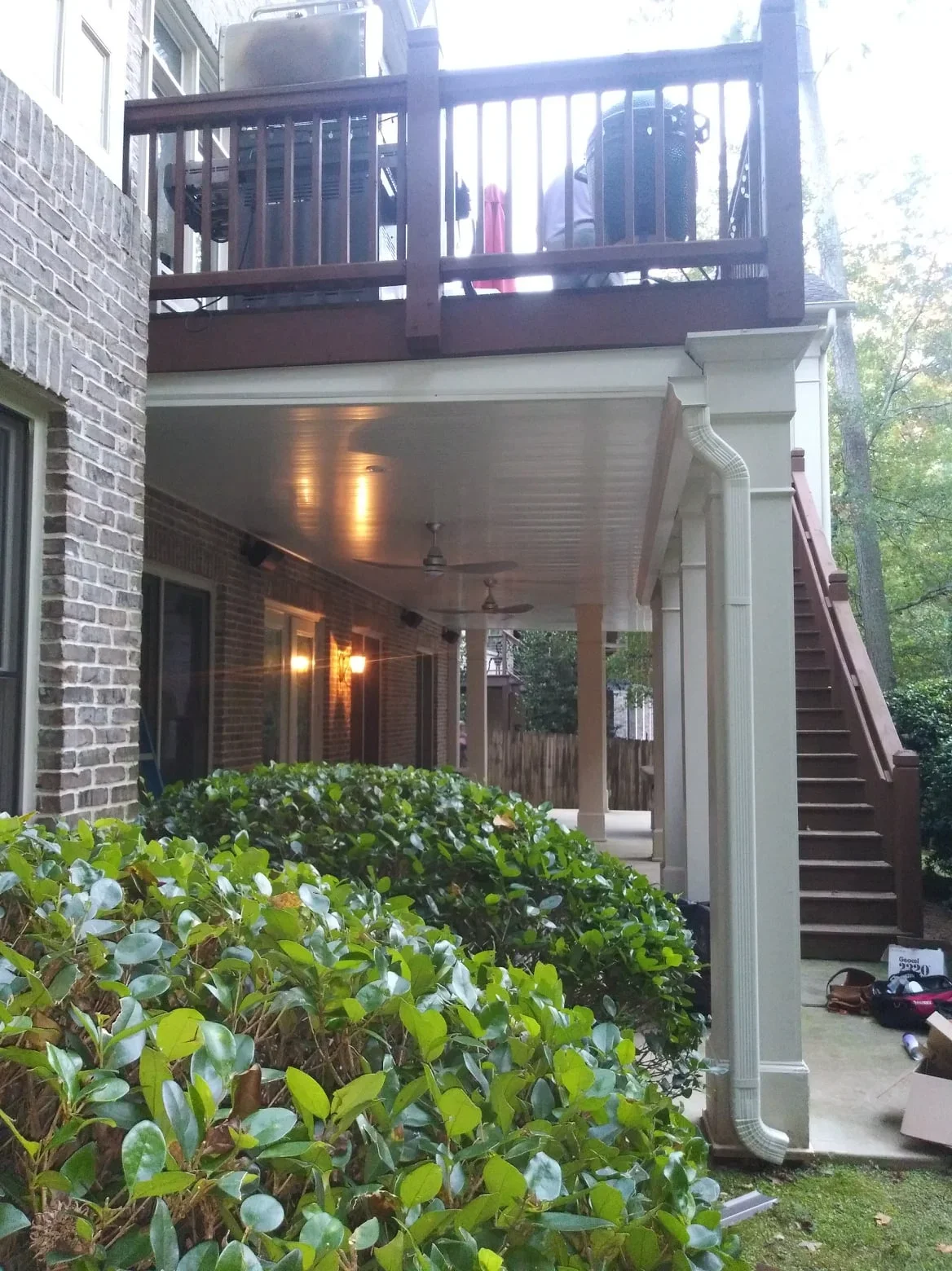 Waterproof under-deck system with white aluminum ceiling and lighting beneath elevated deck