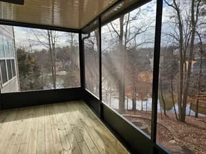 Screened room with composite deck overlooking bare trees and wooded area