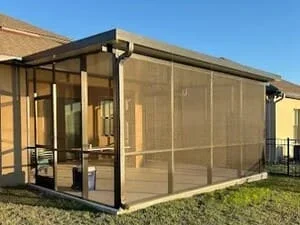 Black-framed screen room with full screening and metal roof structure in backyard setting