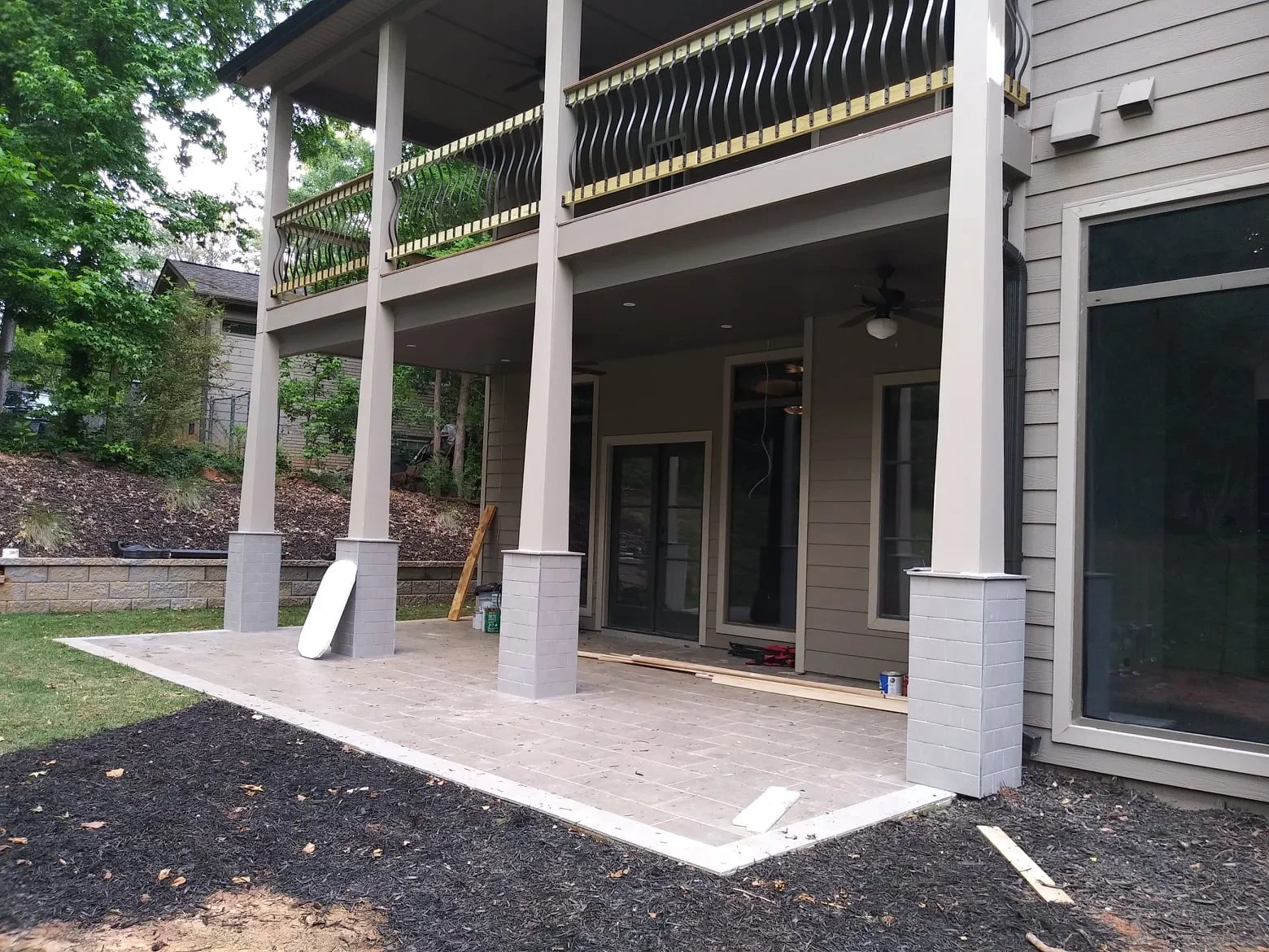 Under-deck drainage system with concrete patio, composite posts, and elevated deck structure