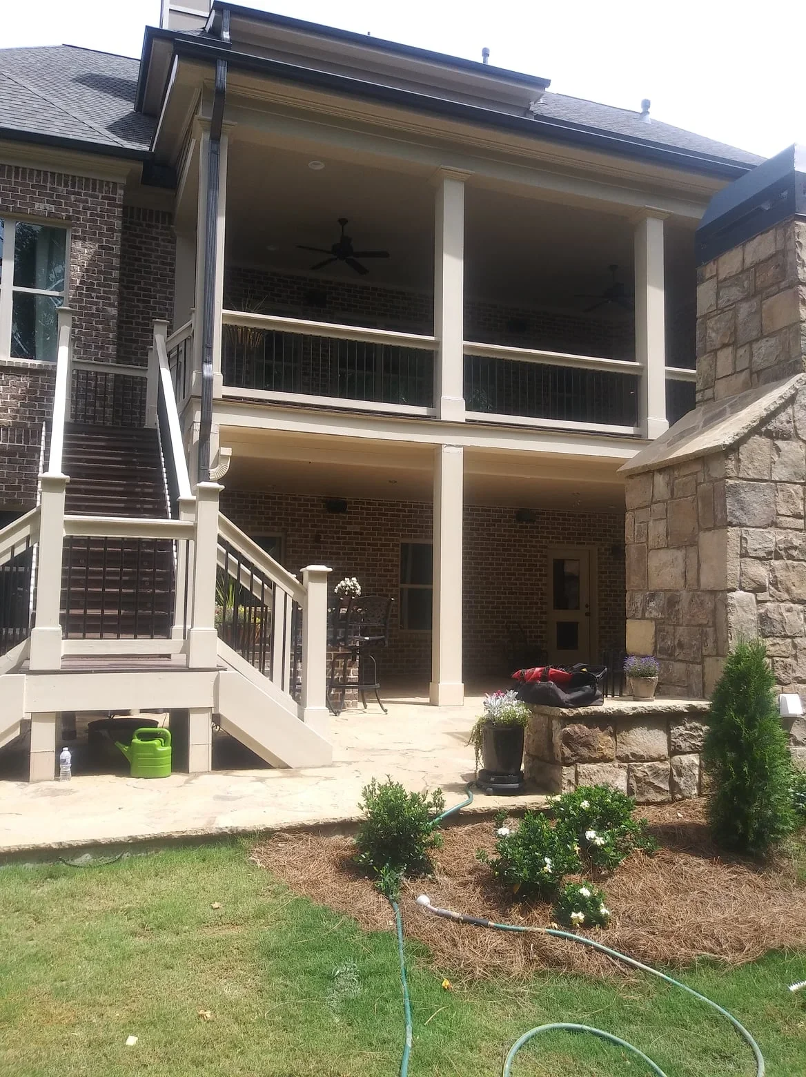 Two-story screen room with white frame, black mesh, and under-deck system on brick home