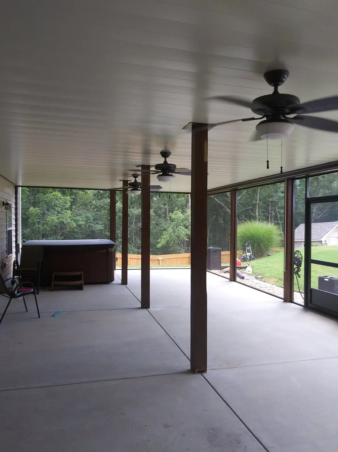 Under-deck system with white aluminum ceiling, support posts, screened walls, and ceiling fans